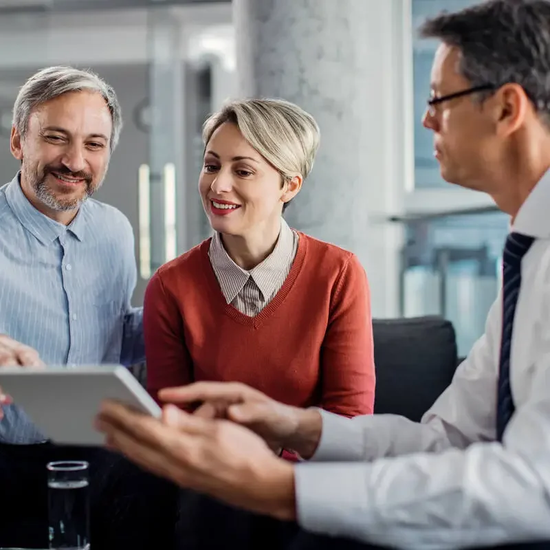 happy-mid-adult-couple-using-touchpad-with-their-financial-consultant-in-the-office-
